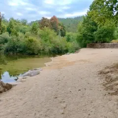 Tranquila playa fluvial en Fornelos de Montes, con arena dorada, aguas cristalinas y rodeada de exuberante vegetación.