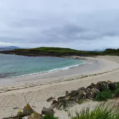 La serena playa Santa Marta de Cangas, con sus aguas turquesas y arena dorada, invita a la calma bajo un cielo nublado.