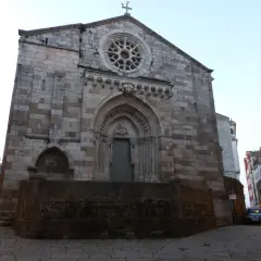 La iglesia de Santiago a Coruña, con su fachada de piedra y rosetón, se alza imponente en una calle adoquinada.