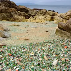 La praia dos cristais, una playa de guijarros de vidrio pulido por el mar, rodeada de rocas y con el océano al fondo.