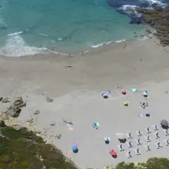 Vista aérea de la playa Paxariñas con gente disfrutando del sol y el mar.