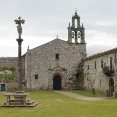El monasterio de Aciveiro, con su iglesia de piedra y campanario, se alza majestuoso. Un cruceiro antiguo preside el patio.
