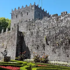 El imponente castillo de Sotomayor se alza sobre un jardín cuidado, con sus muros de piedra y almenas bajo un cielo azul.
