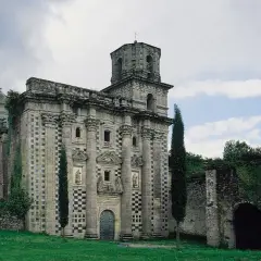 El imponente monasterio de Monfero, con su fachada de piedra y torre octogonal, se alza entre la vegetación, evocando historias de tiempos pasados.