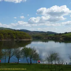 El embalse de Vilasouto, con sus aguas serenas reflejando el cielo azul y las verdes colinas, invita a disfrutar de un día tranquilo.