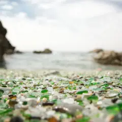 La playa de los cristales, un tesoro de vidrio pulido por el mar, se extiende ante rocas y el océano.