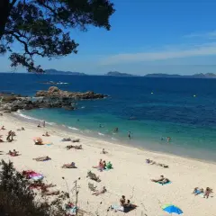 Gente disfrutando del sol y el mar en la **praia do tombo do gato**. Aguas cristalinas y arena dorada bajo un cielo azul.