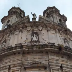 La imponente fachada de la iglesia de la Virgen Peregrina se alza bajo un cielo nublado, con sus torres y estatuas de piedra.