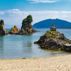 Rocas emergiendo del mar azul, un monumento en una de ellas, y la arena dorada de las playas cerca de Viveiro.