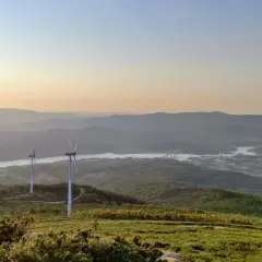 Vistas del monte Xiabre con molinos de viento y un río al atardecer.