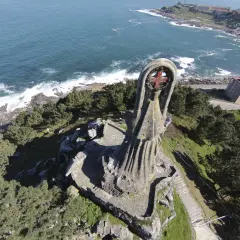 La Virgen de la Roca, una imponente estatua de piedra, vigila el mar azul desde un acantilado verde.