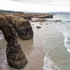 Impresionantes arcos de roca natural en la playa de Ribadeo, con el mar Cantábrico rompiendo suavemente en la arena.
