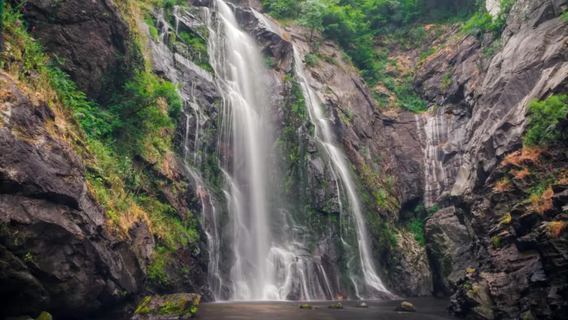La Fervenza das Hortas, una cascada imponente que desciende por rocas cubiertas de vegetación, creando un espectáculo natural.