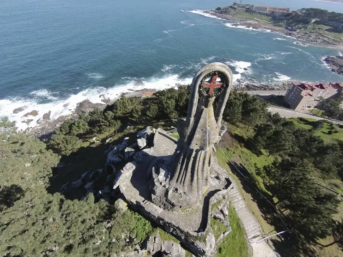 La Virgen de la Roca, una imponente escultura de piedra, vigila el mar azul desde una colina verde.