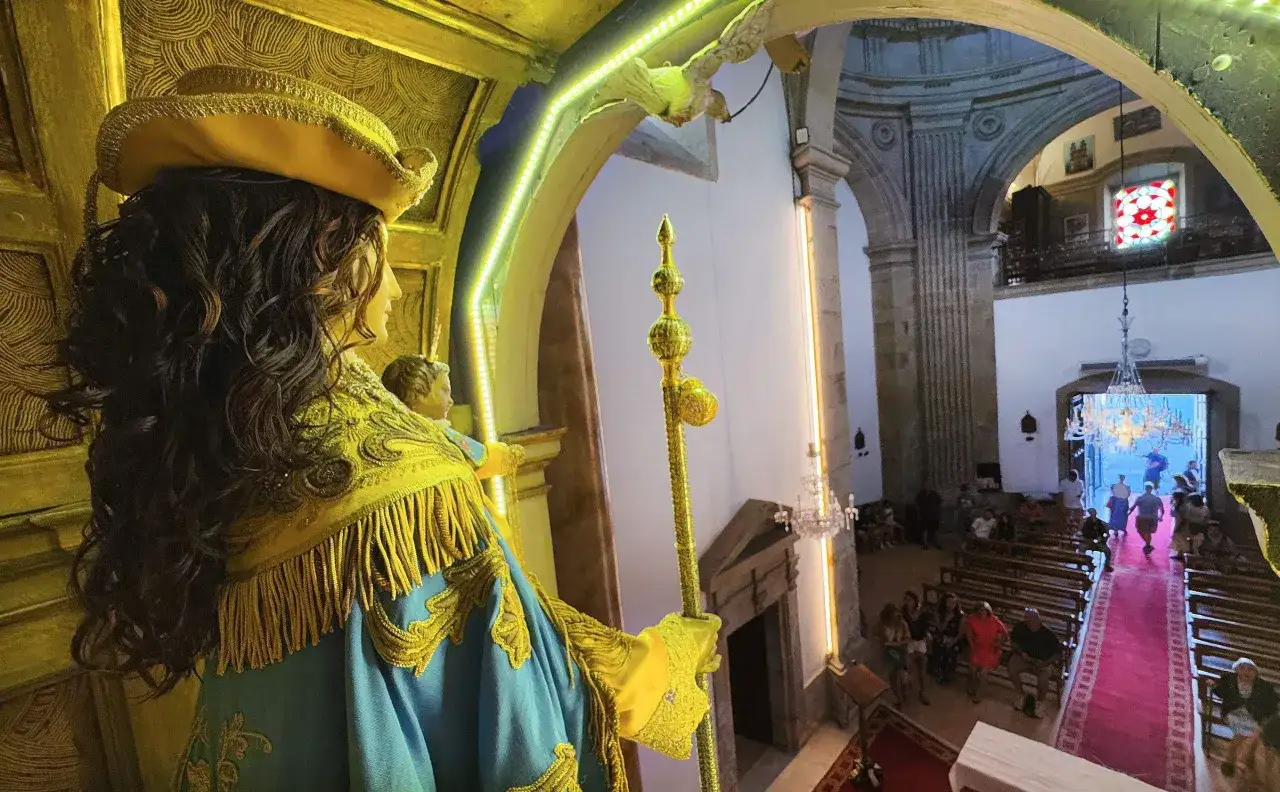 Estatua de la Virgen Peregrina en la iglesia, con su manto azul y dorado. Al fondo, feligreses y una alfombra roja.