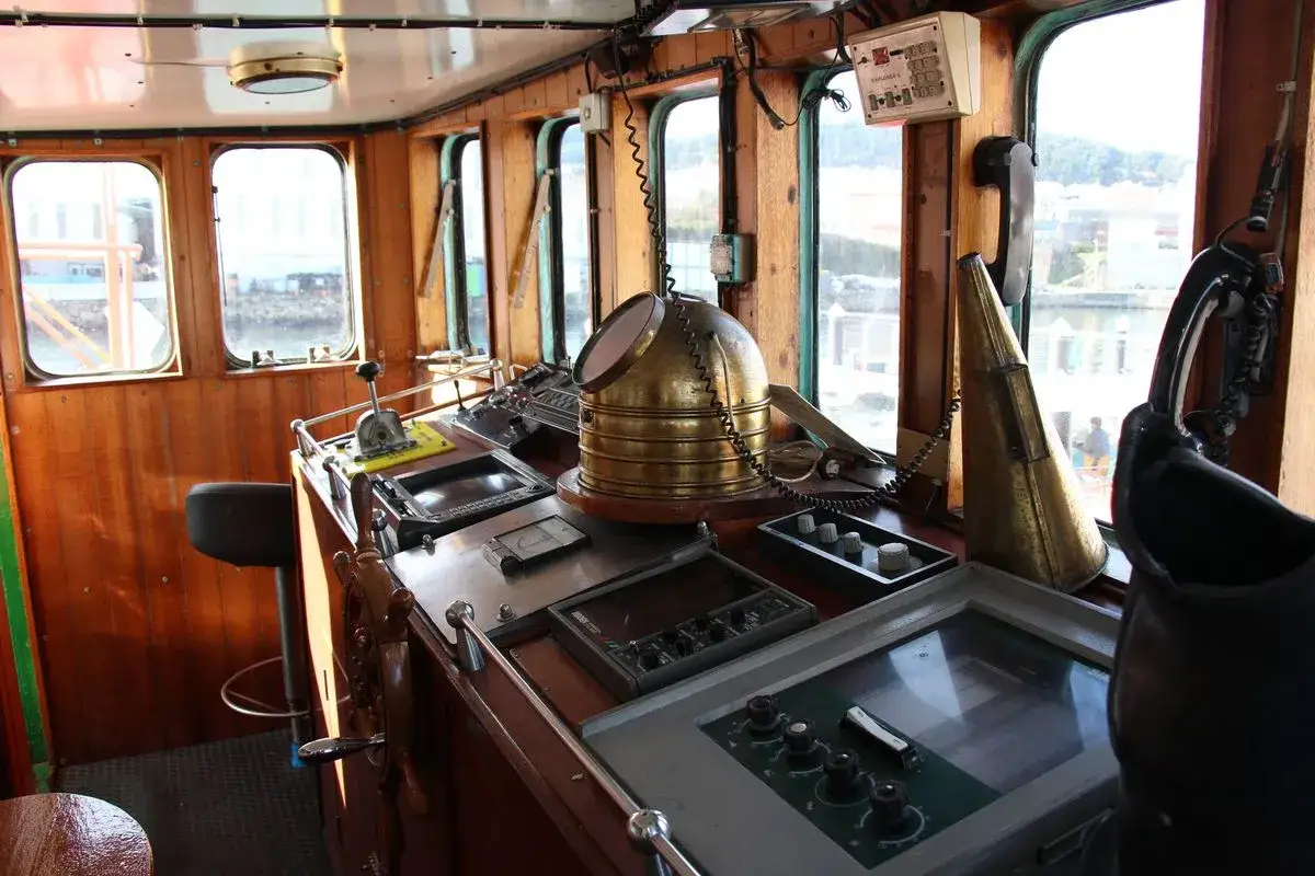 Timón y consola de un barco museo en Burela. Instrumentos náuticos, timón de madera y vistas al mar.