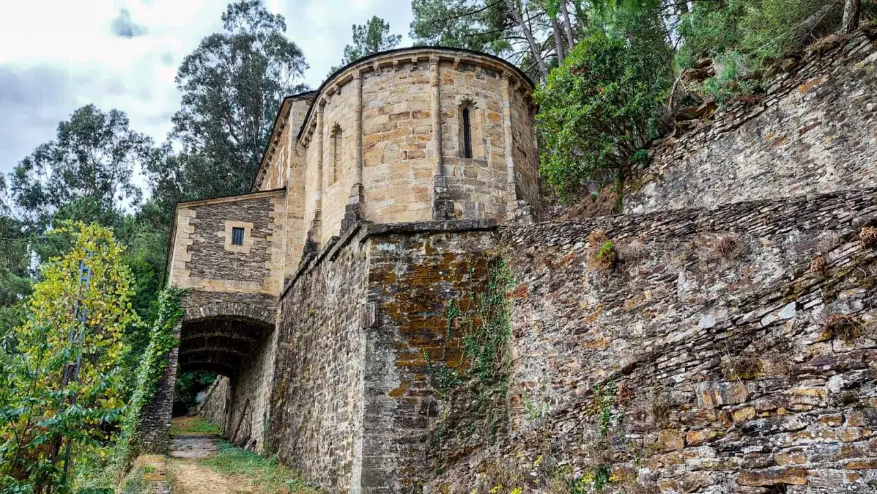 Antiguo castillo de Chantada con muros de piedra cubiertos de musgo y vegetación, rodeado de árboles.