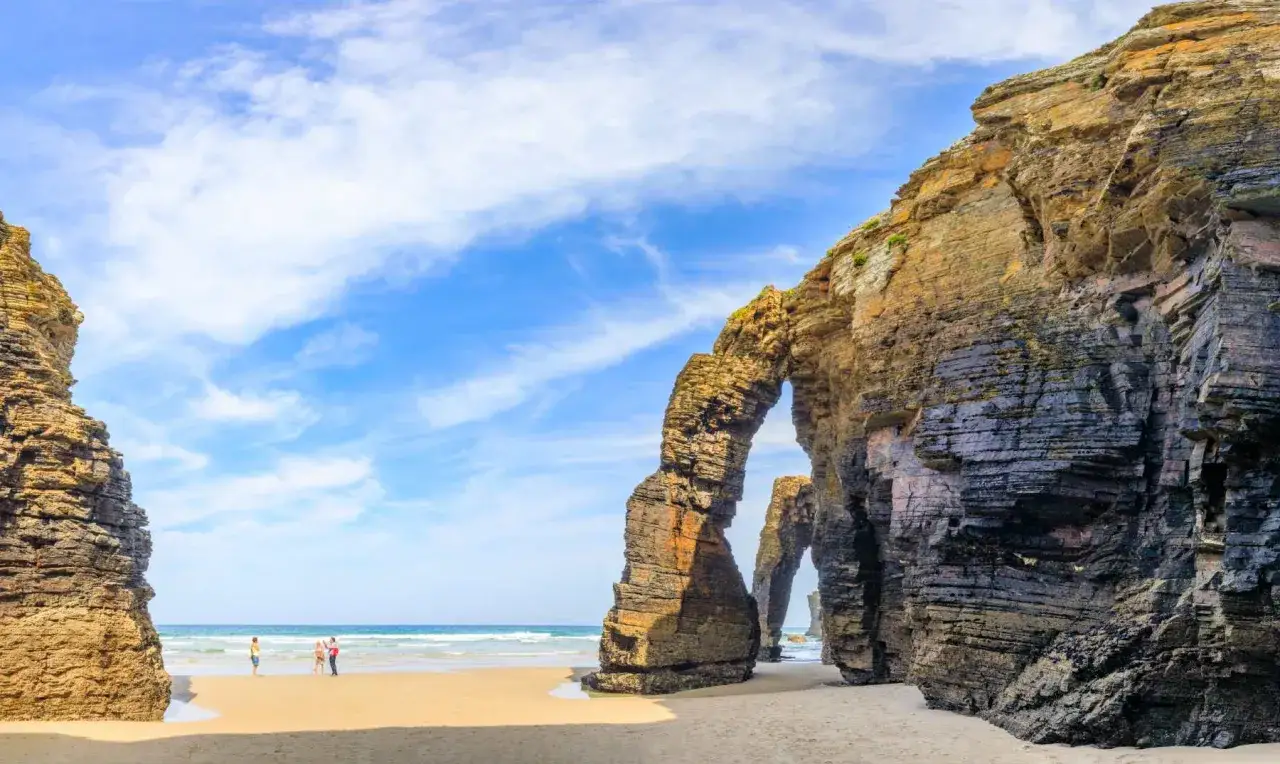 Impresionantes arcos rocosos en la playa de Ribadeo, con el mar y el cielo azul de fondo.